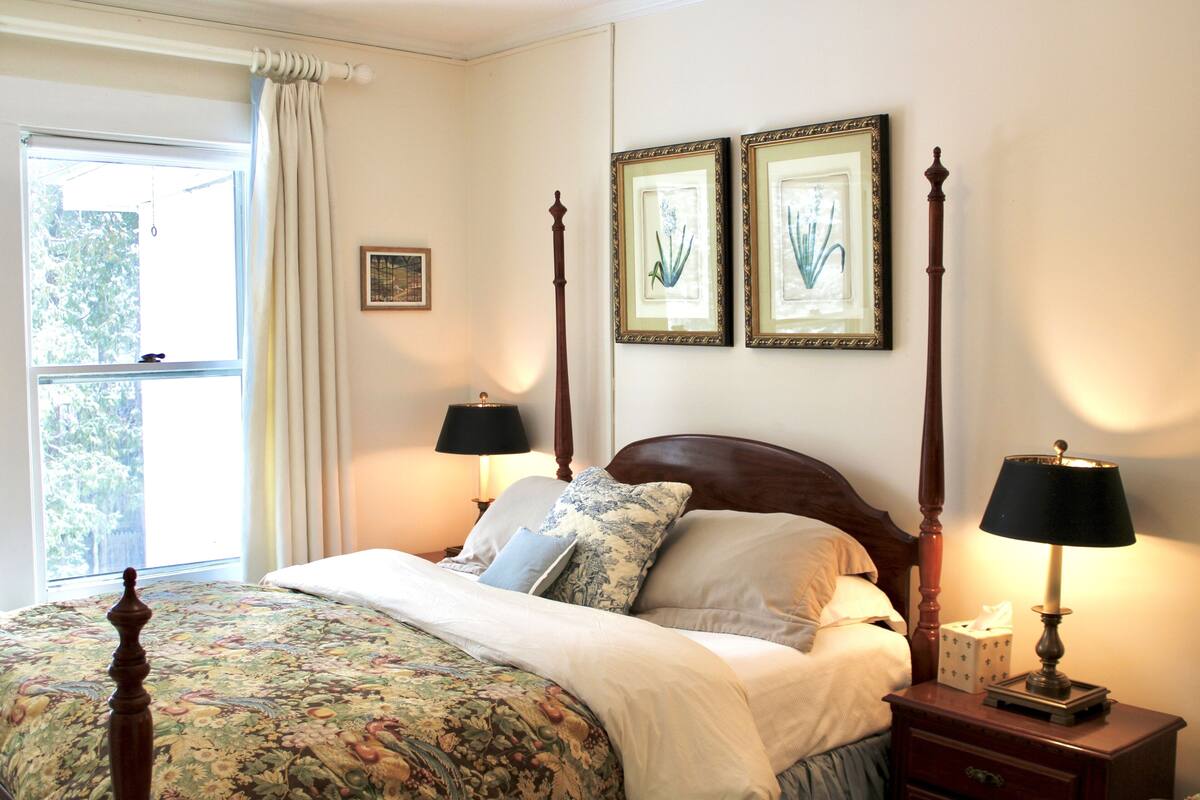 A neatly made bed with floral bedding, a wooden headboard, and two bedside lamps.
