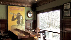 A bar area with wooden furniture, a large poster, and a window with a view of trees.