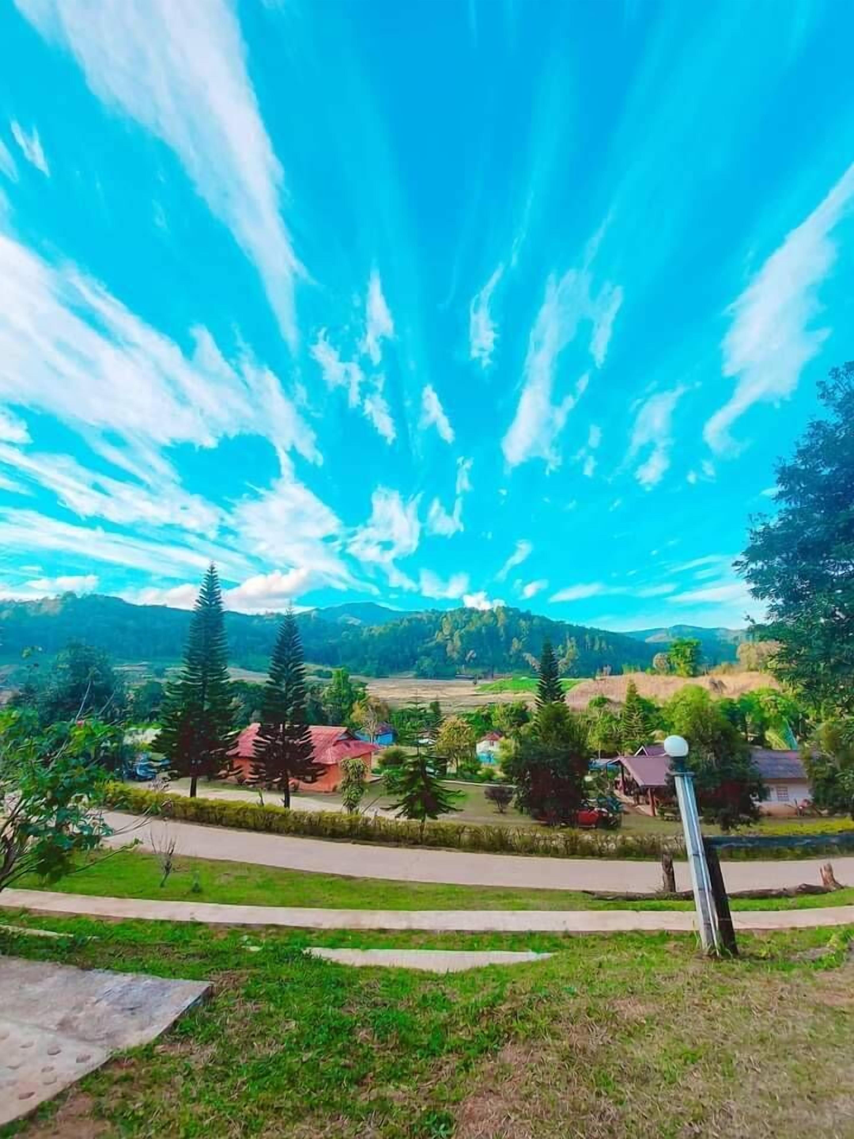 Un paysage rural caractérisé par un ciel dégagé, des champs verdoyants et des maisons éparpillées.