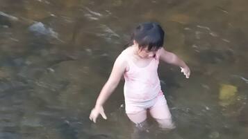 Criança de biquíni rosa brincando em águas rasas.