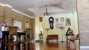 Un salon spacieux doté d’un plancher en bois, d’un mur en briques, d’une grande horloge et d’un banc.