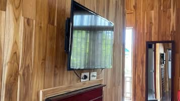 Ein Zimmer mit Holzwandverkleidung, einem an der Wand befestigten Flachbildfernseher und einem Kamin mit rotem Rahmen.
