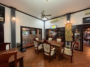 A dining area with a wooden table and chairs, a ceiling fan, and a tiled floor. - Luang Prabang Inn (Luang Prabang)