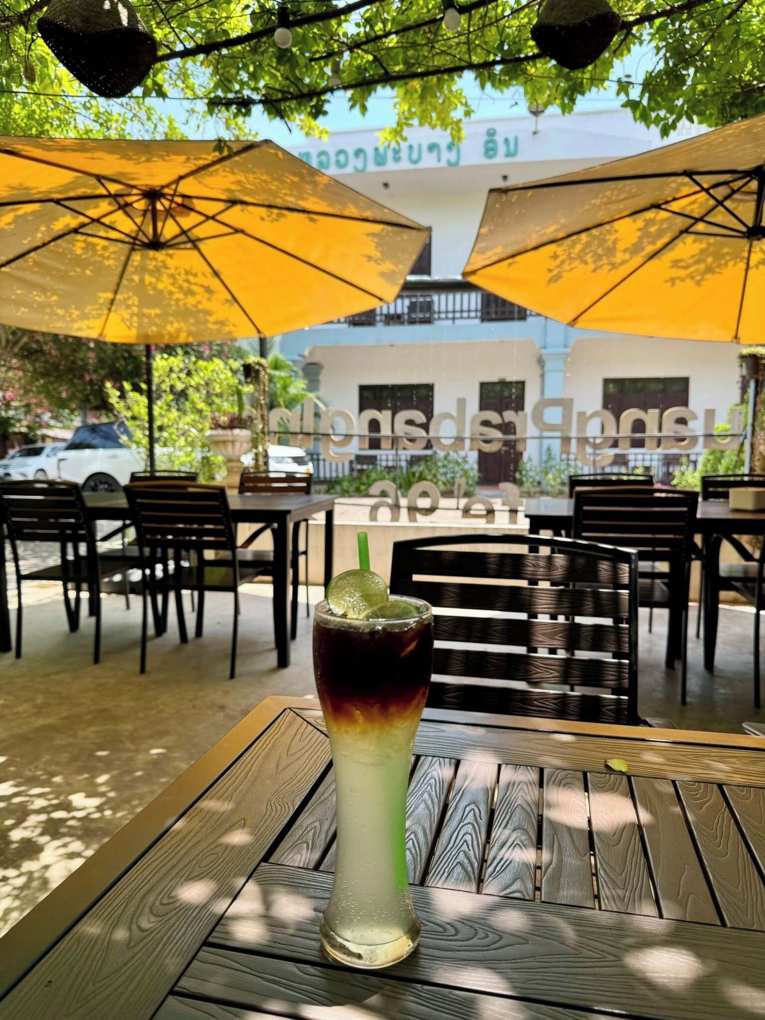 A table with a drink and two yellow umbrellas in an outdoor setting.