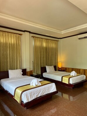 A hotel room with two beds, a wooden headboard, a marble floor, and a large window with curtains. - Luang Prabang Inn (Luang Prabang)