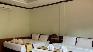 Ein Hotelzimmer mit zwei Betten, jeweils mit weißen Leinen und Handtüchern, einem Holz-Kopfteil, einer Nachttischlampe und einem Marmorboden.