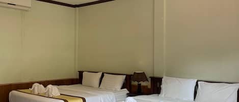 Ein Hotelzimmer mit zwei Betten, jeweils mit weißen Leinen und Handtüchern, einem Holz-Kopfteil, einer Nachttischlampe und einem Marmorboden.
