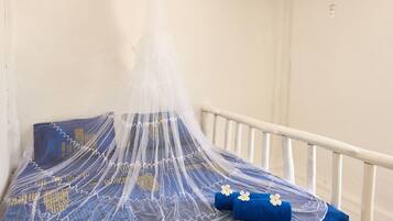 A bed with a mosquito net and blue bedding.