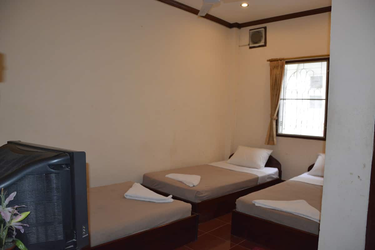 A small hotel room with two single beds, a television, and a window with curtains.