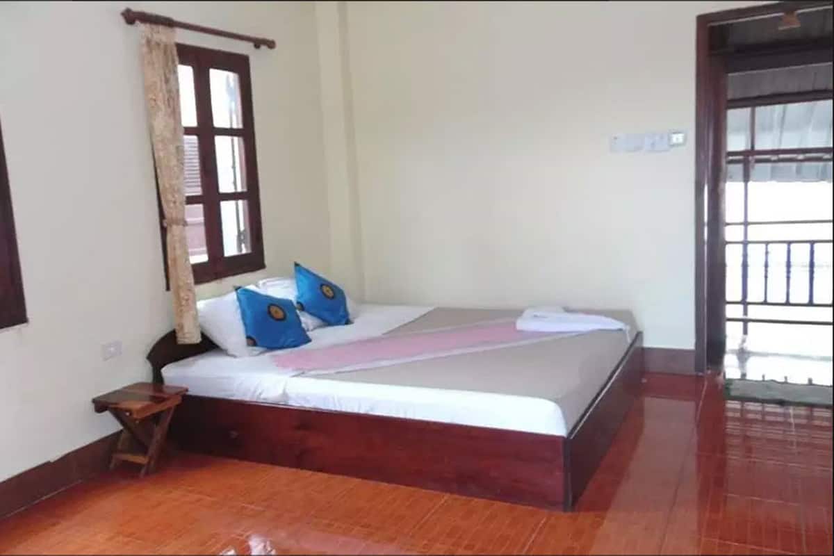A bedroom with a wooden bed, a nightstand, and a window with shutters.