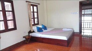 A bedroom with a wooden bed, a nightstand, and a window with shutters.