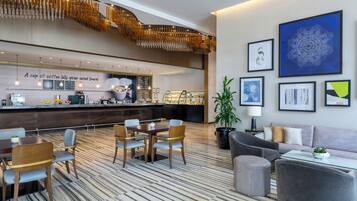 A modern hotel lobby with a central bar, seating area, and artwork on the walls.