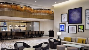 A modern hotel lobby with a bar area, seating arrangements, and artwork on the walls.