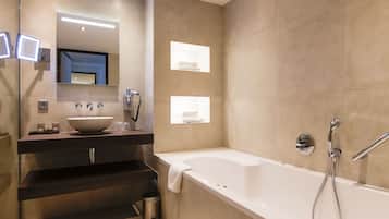 A modern bathroom with a large bathtub, a vanity with a sink, and a mirror.