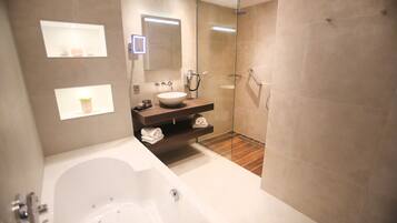 A modern bathroom with a large bathtub, a glass-enclosed shower, and a vanity with a sink and mirror.