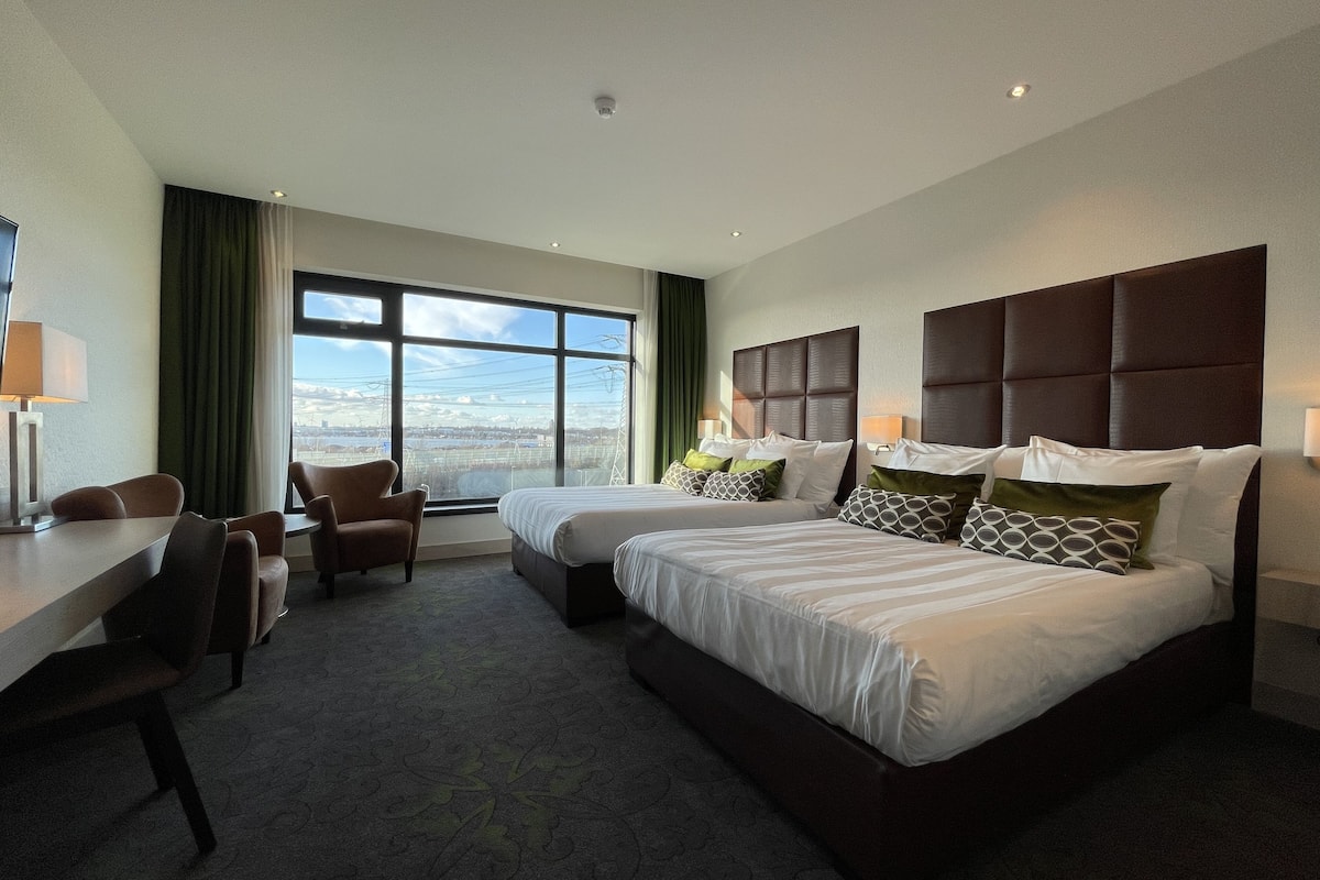 A hotel room with two beds, a desk, and a chair.