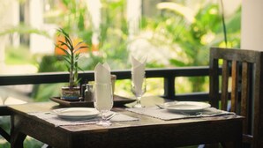 A dining table set with plates, glasses, and a potted plant. - SR Sofia Villa Hotel (Siem Reap)