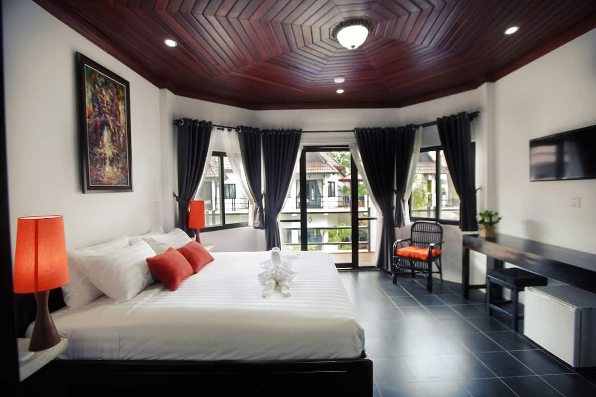 Una habitación de hotel con cama, escritorio, silla y televisor.