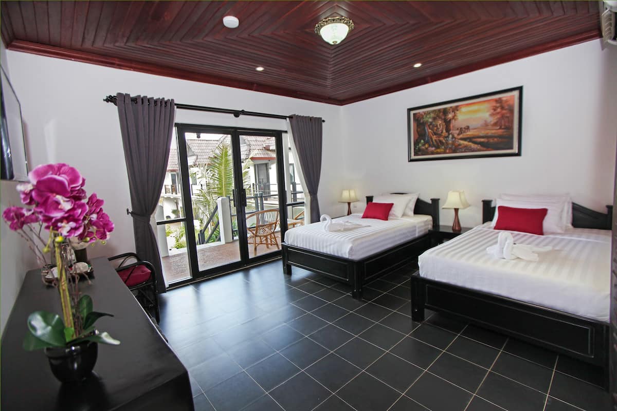 Habitación de hotel con dos camas, una mesa de comedor y vistas al exterior.