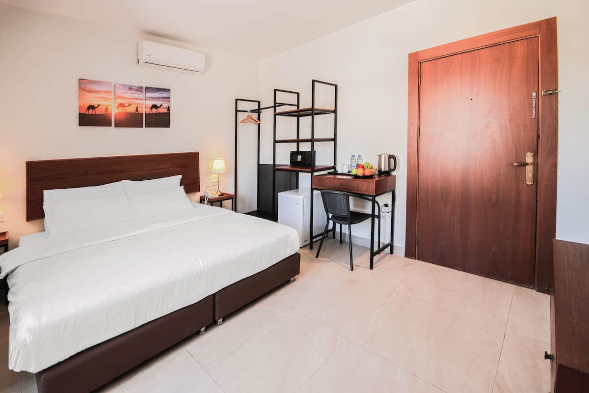 Quarto com cama, escrivaninha, cadeira e porta de madeira.