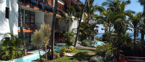 A resort with a swimming pool, palm trees, and a view of the ocean.