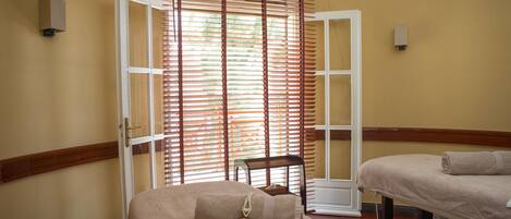 A room with a bed, a chair, and a window with blinds.