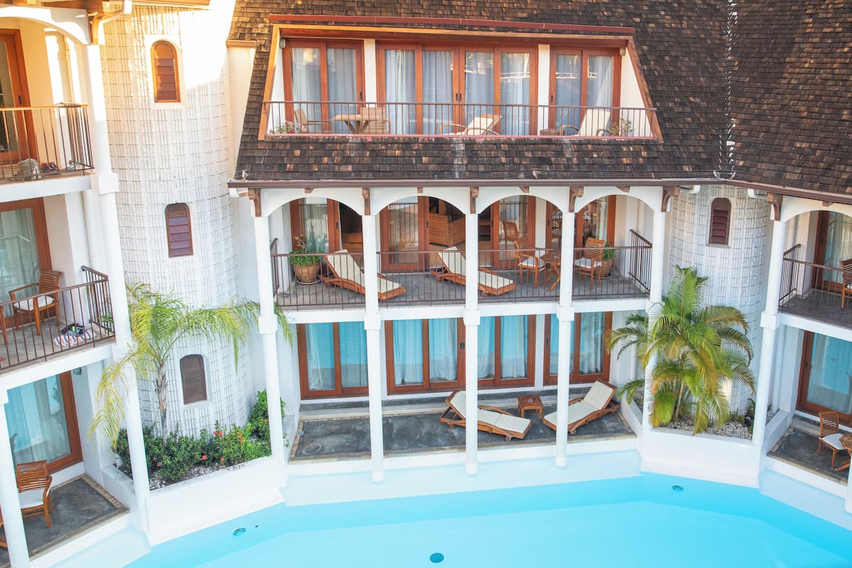Un hotel de varios pisos con balcones, piscina y zonas de estar al aire libre.
