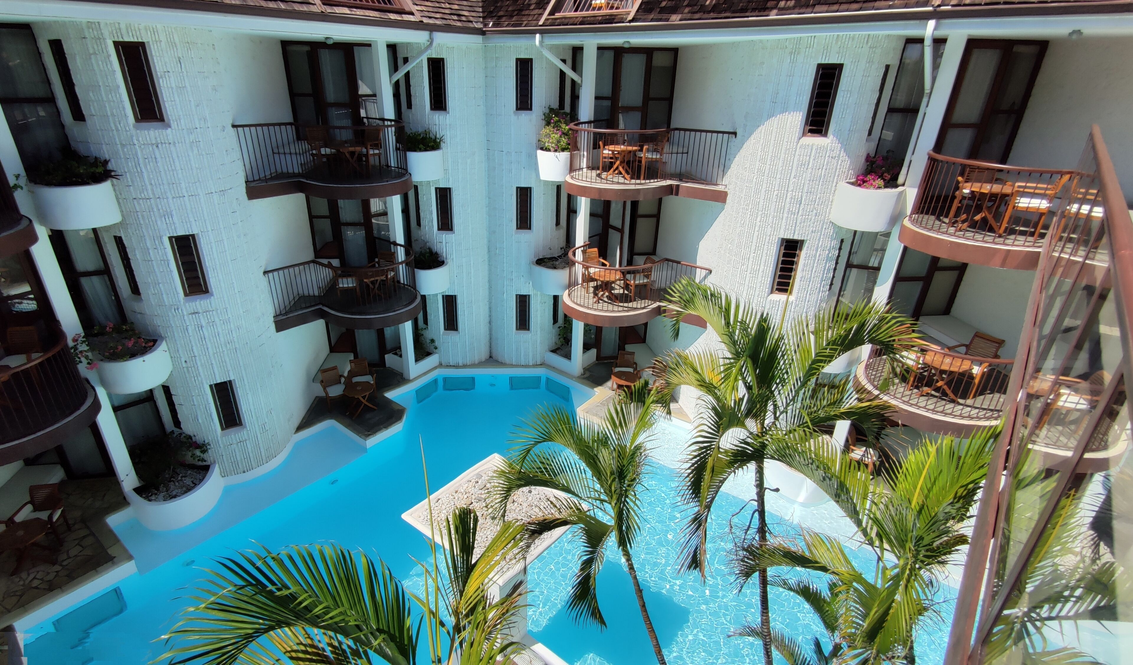 A multi-level indoor pool with multiple balconies, each with seating and potted plants.