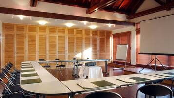 Un salón de conferencias con una larga mesa, sillas, una pantalla de proyector y una pizarra.