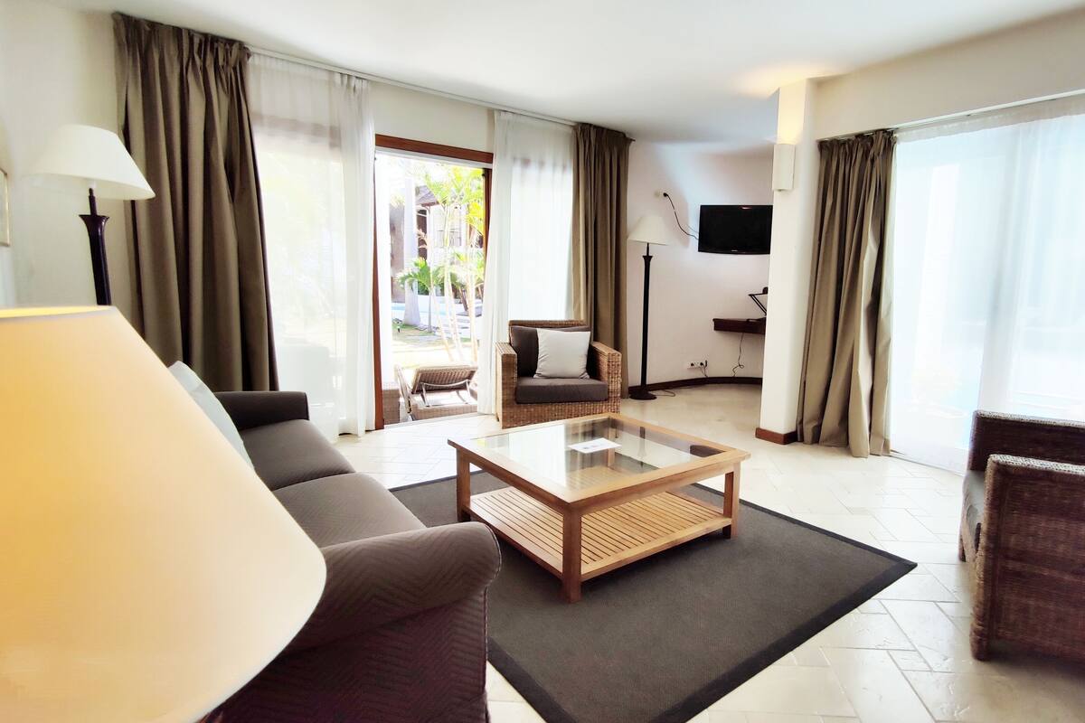 Una sala de estar moderna con un sofá, un sillón y una mesa de centro de vidrio.