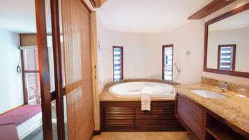 A bathroom with a large bathtub, two sinks, and a wooden vanity.