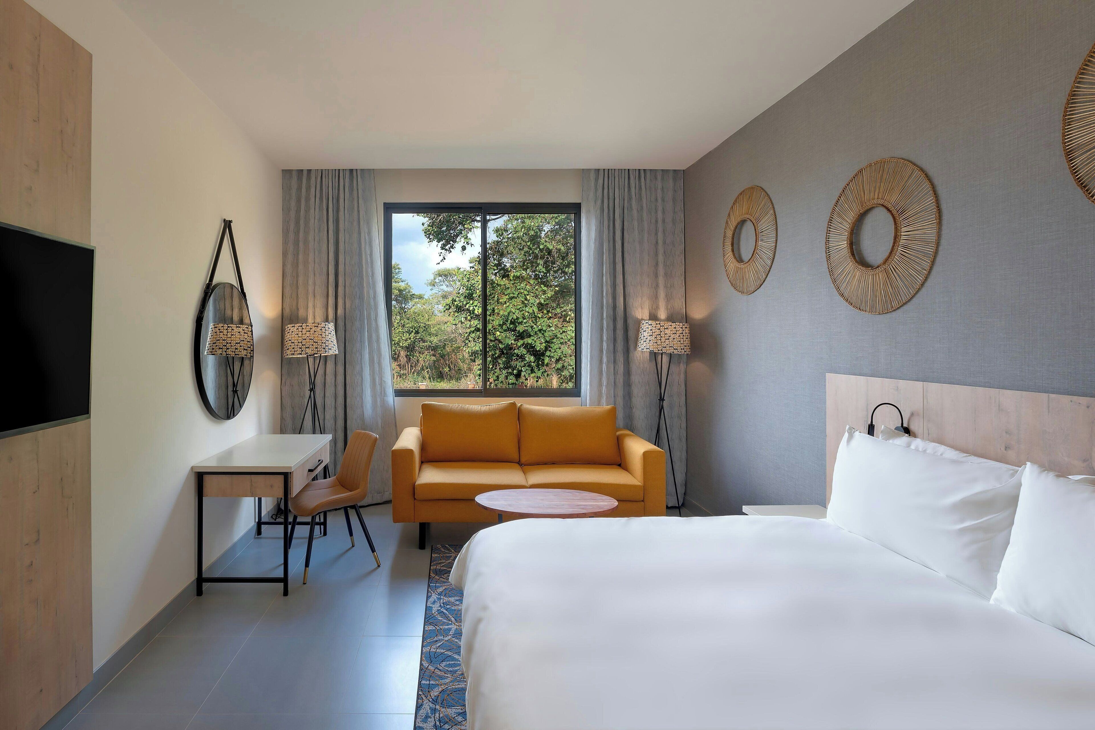 Une chambre d’hôtel moderne équipée d’un grand lit, d’un canapé, d’un bureau et d’une télévision.