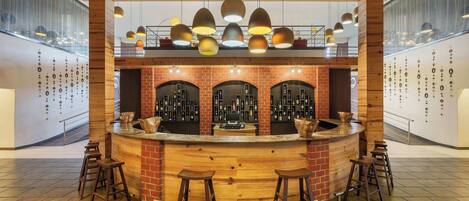 A bar area with wooden counter, stools, and hanging pendant lights.