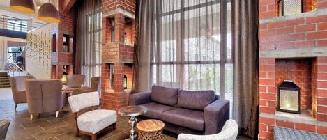 A modern interior with a brick fireplace, comfortable seating, and large windows.