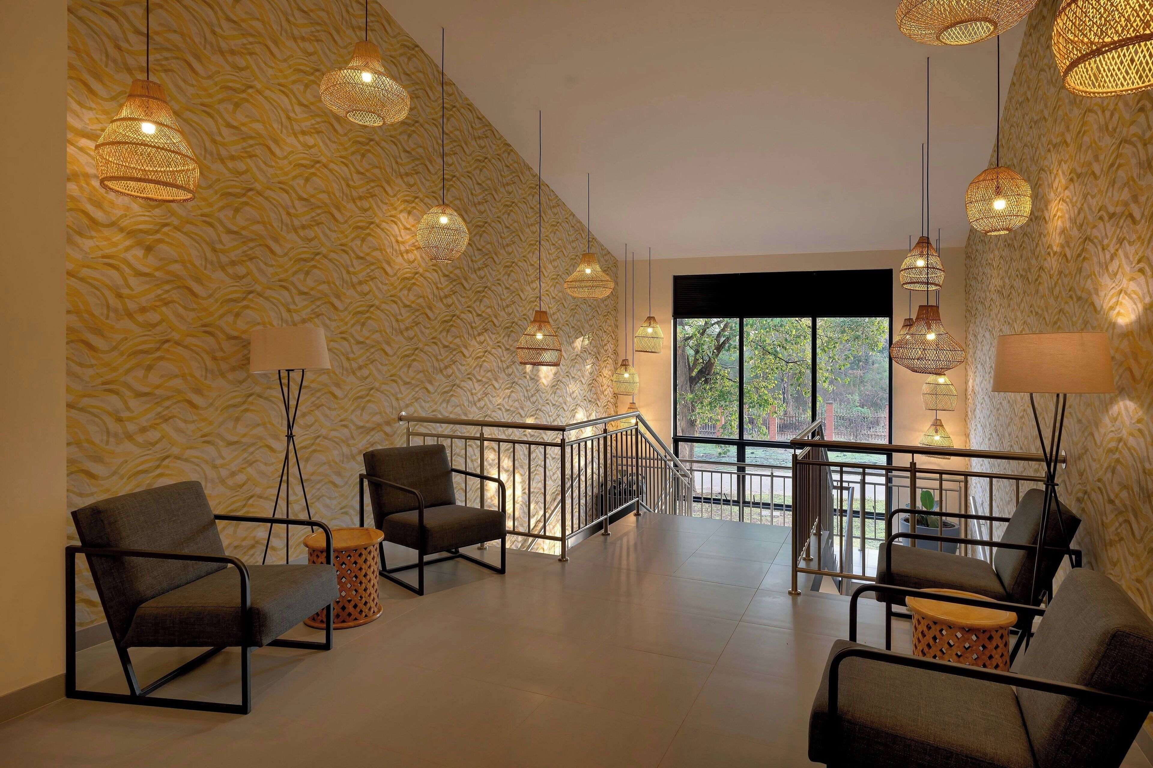 A modern lobby with patterned wallpaper, a staircase, and multiple seating areas.