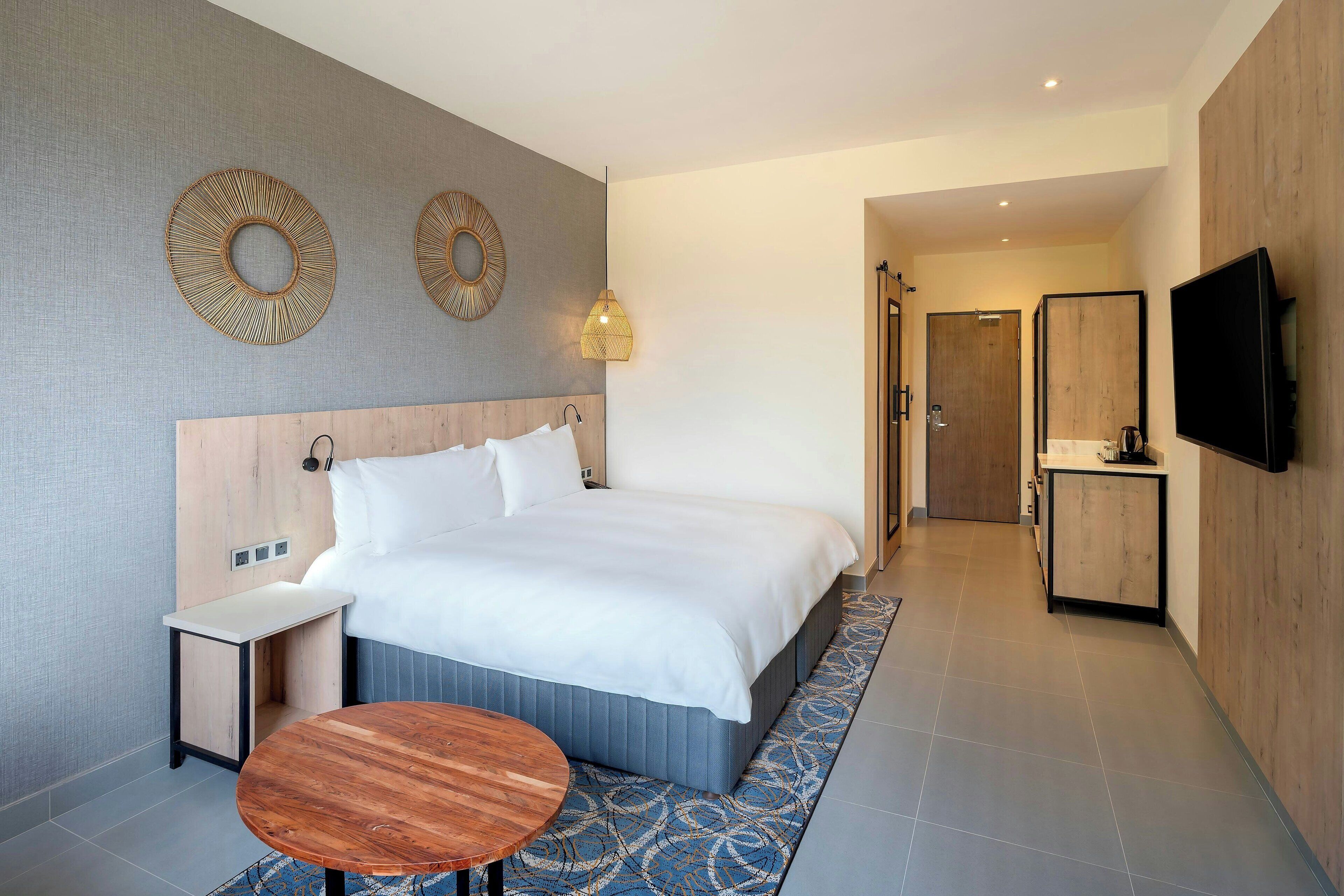 Een moderne hotelkamer met een groot bed, nachtkastjes, een televisie en een klein tafeltje.