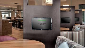A modern hotel lobby with a Courtyard Marriott sign, seating areas, and a reception desk.