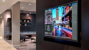 Un moderno vestíbulo de hotel con una gran pantalla digital mostrando un paisaje urbano.