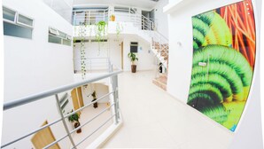 Ein mehrgeschossiges Interieur mit einer Treppe, Topfpflanzen und einem großen Wandgemälde.