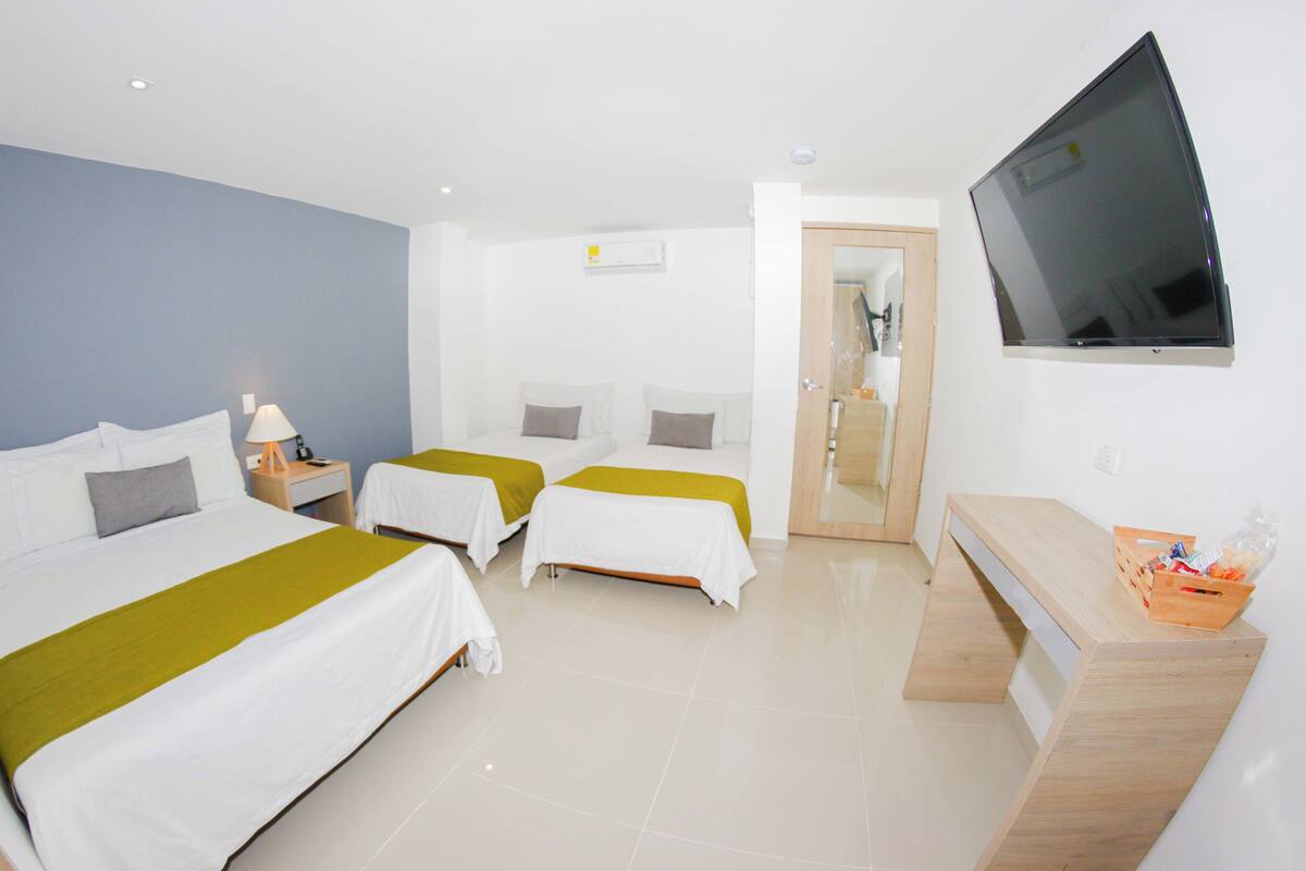 A hotel room with two single beds, a TV, a desk, and a mirror.