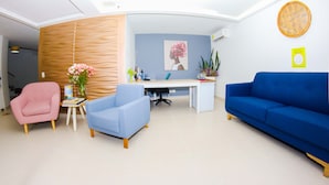 A modern living room with a blue sofa, a pink chair, and a blue armchair. There is a desk with a computer and a plant. - Hotel Boutique Laureles Medellín (Medellín)