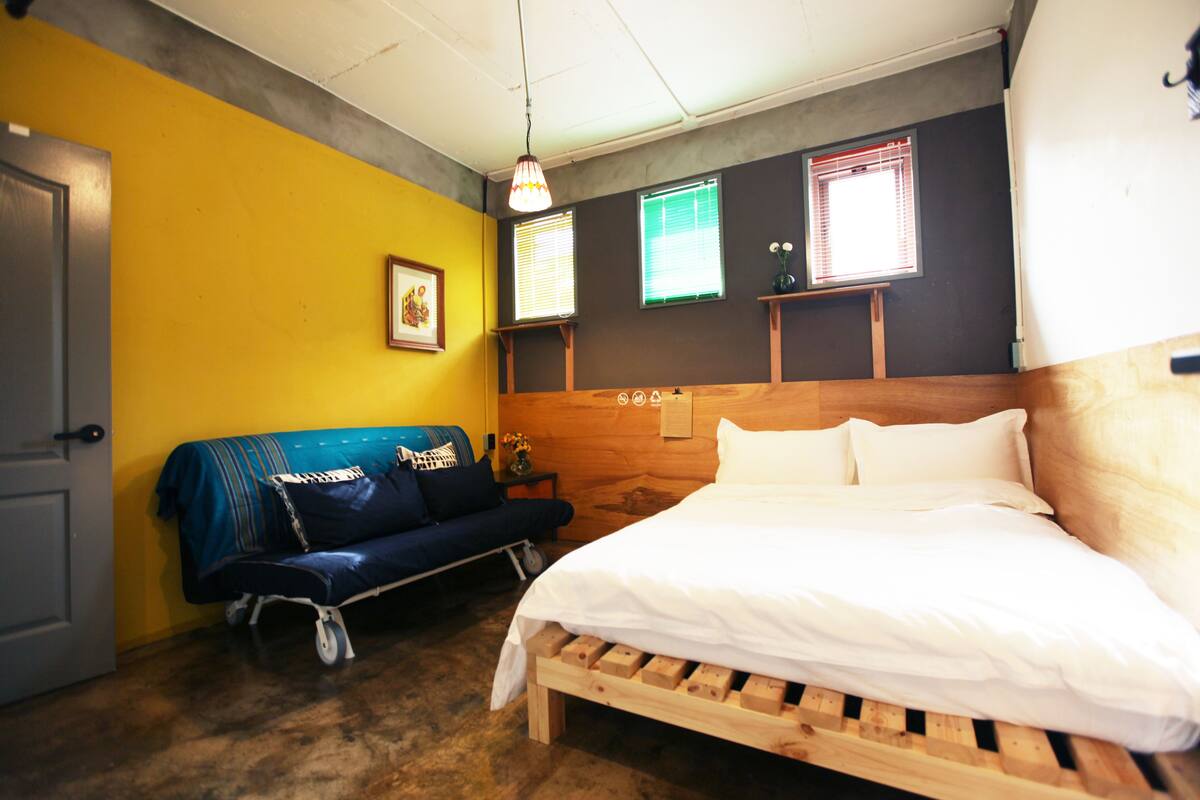 Una habitación con una cama, un sofá y un cabecero de madera.