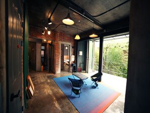 A modern room with exposed brick walls, a large sliding glass door to a balcony, and a minimalist furniture setup including a table and two chairs. - Hongdae Guesthouse Pajamaparty - Hostel (Seoul)