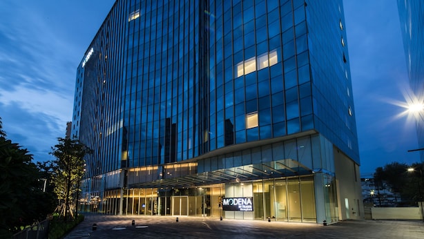 A modern hotel with a glass facade, a prominent entrance, and a sign reading "MODENA". - Modena by Fraser Bangkok Hotel Residences (Bangkok)