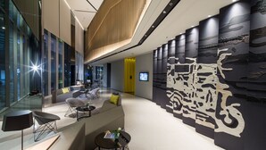 A modern lobby with a seating area, a large wall mural, and a glass facade. - Modena by Fraser Bangkok Hotel Residences (Bangkok)