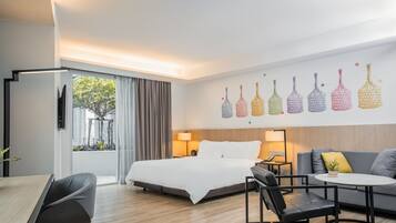 Habitació d'hotel moderna amb un llit gran, un sofà, una taula de menjador i una televisió.