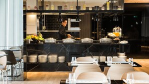 A modern restaurant with a marble counter, neatly arranged tables, and a chef preparing food. - Modena by Fraser Bangkok Hotel Residences (Bangkok)