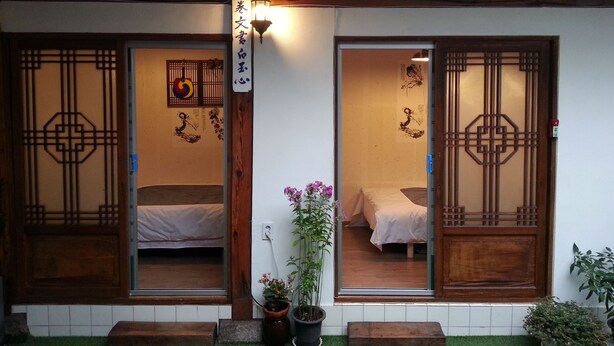 Une pièce de style japonais traditionnel, avec des portes coulissantes, un lit et une petite plante en pot.