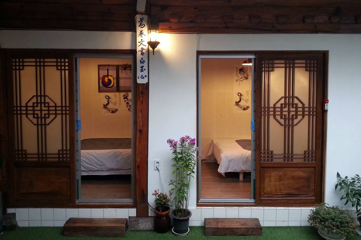 A traditional Japanese-style room with sliding doors, a bed, and a small potted plant.