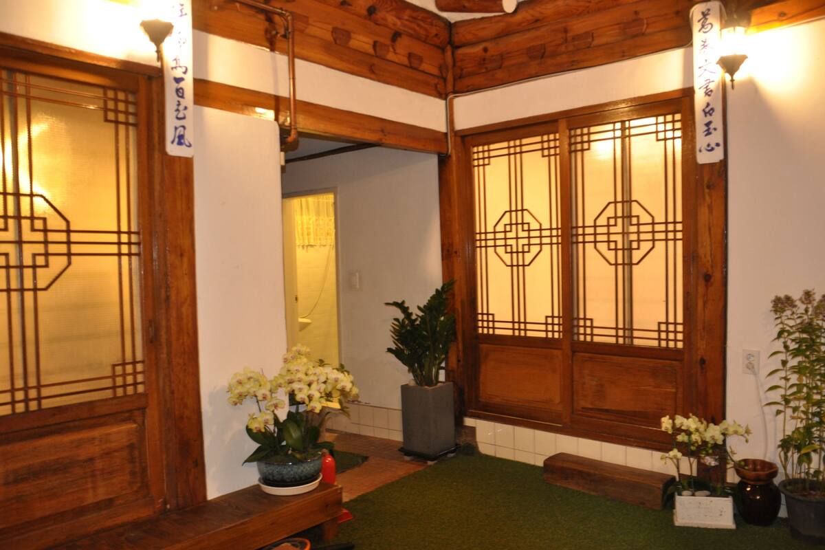 A traditional Japanese interior with wooden doors, a small bench, and potted plants.